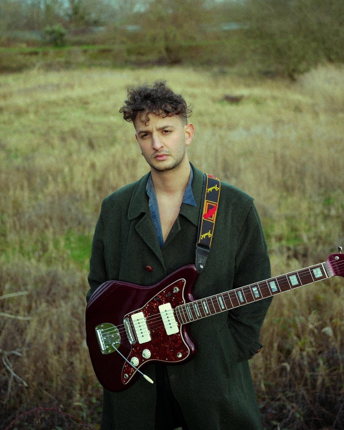 Davide De Santis standing in a field with an electric guitar